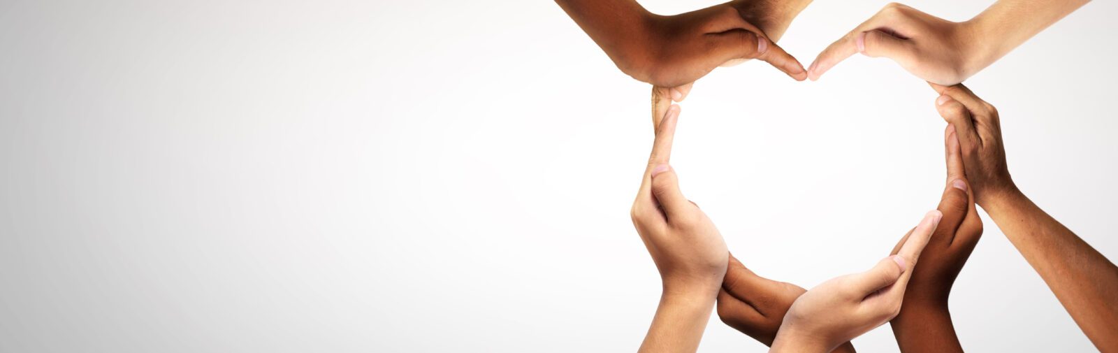 A diverse group of hands joined together to form a heart shape.