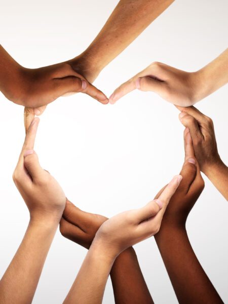 A diverse group of hands joined together to form a heart shape.