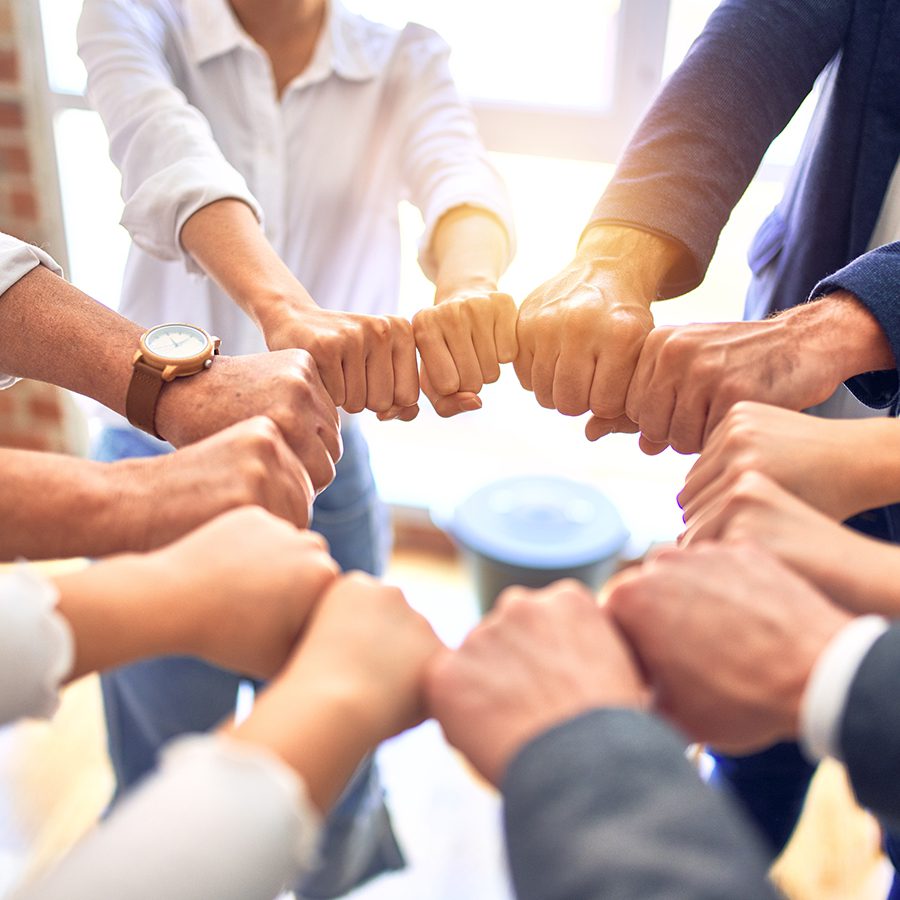 Group of business workers standing bumping fists at the office