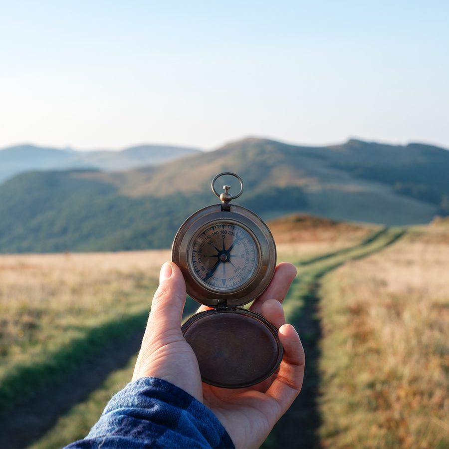 Man with compass in hand on mountains road.