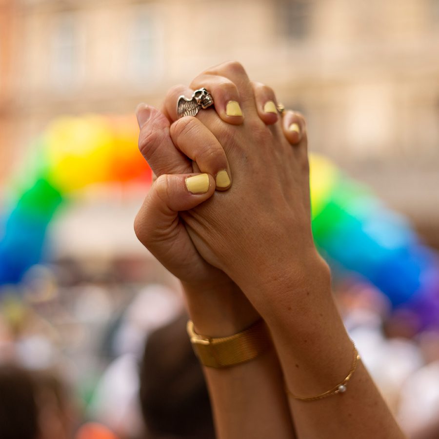 People taking part in LGBT parade, person clasping hands